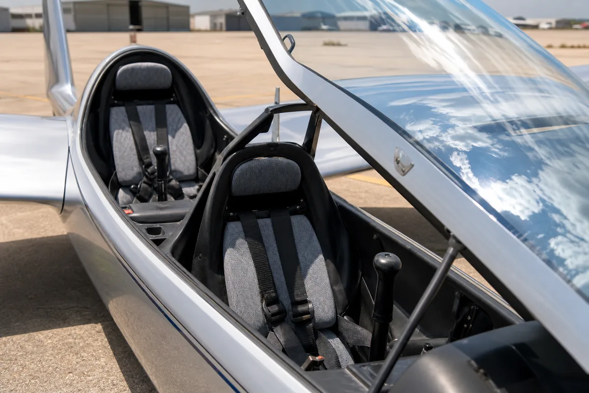 Cockpit ouvert d’un planeur biplace au sol, sièges et manches vides avant le vol